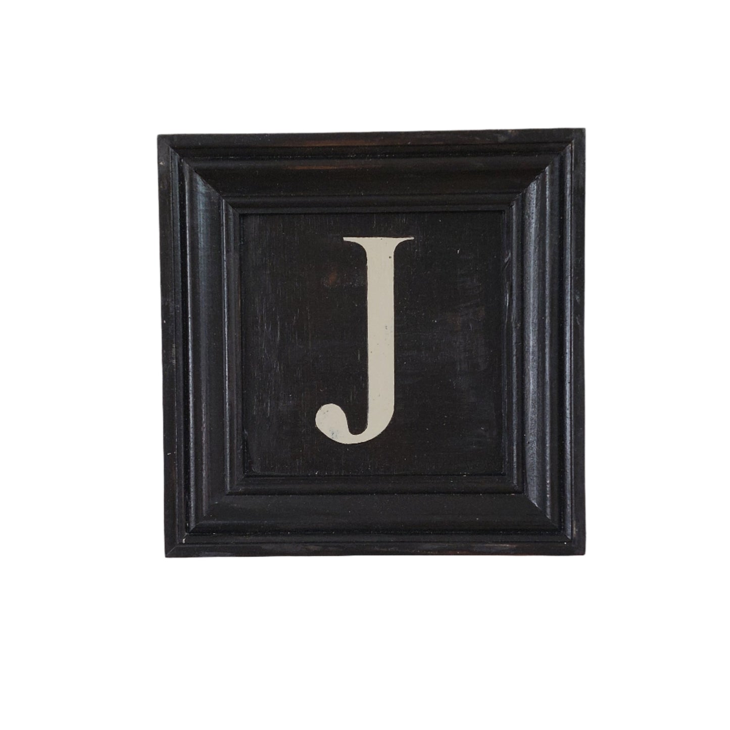 Decorative wall art with a black frame and white letter 'J' on a white background