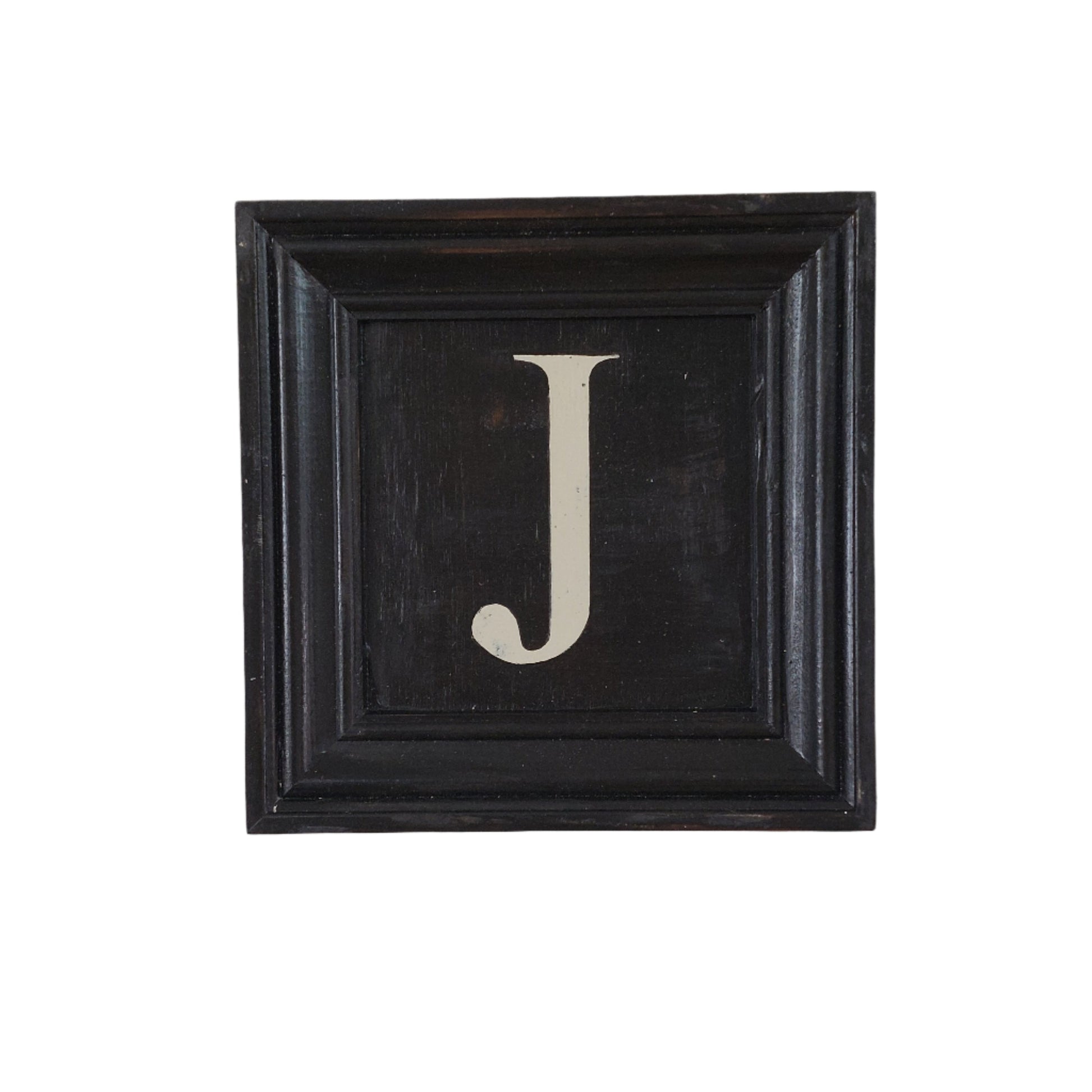 Decorative wall art with a black frame and white letter 'J' on a white background